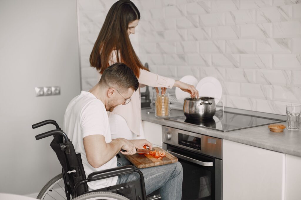 Disabled Man Preparing Food In Kitchen. Cutting vegetables.